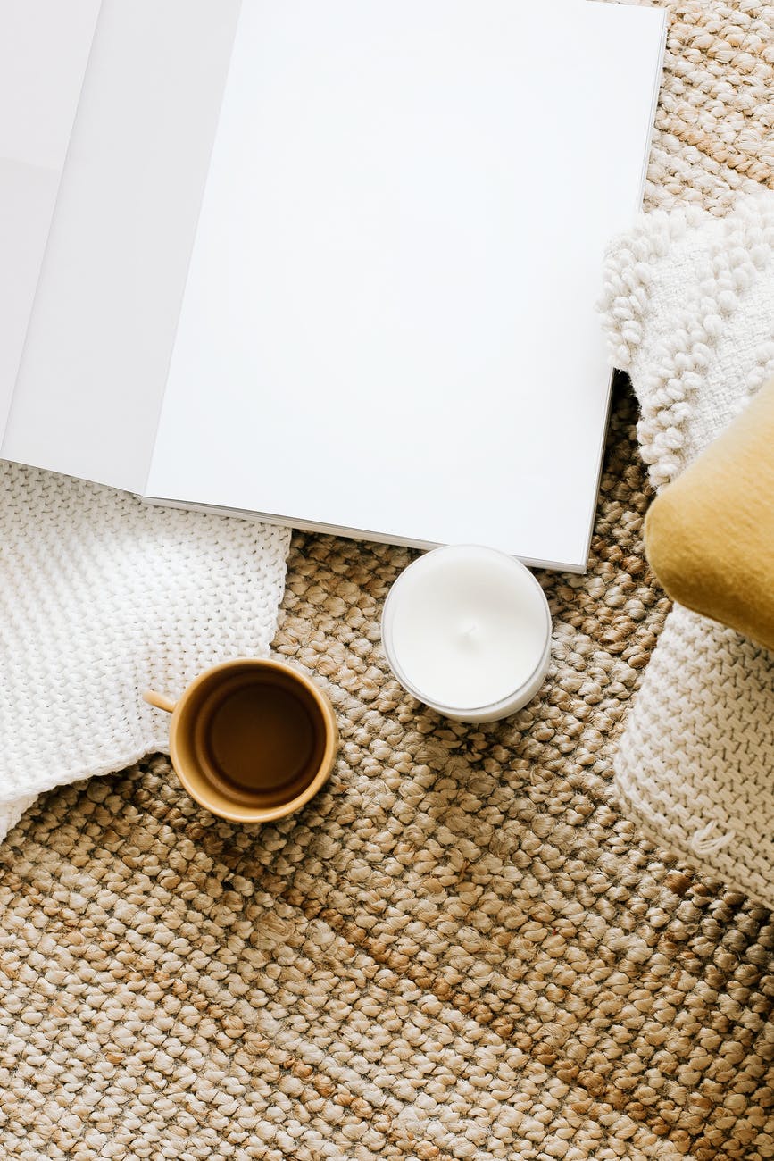 opened diary placed on table near mug and candle