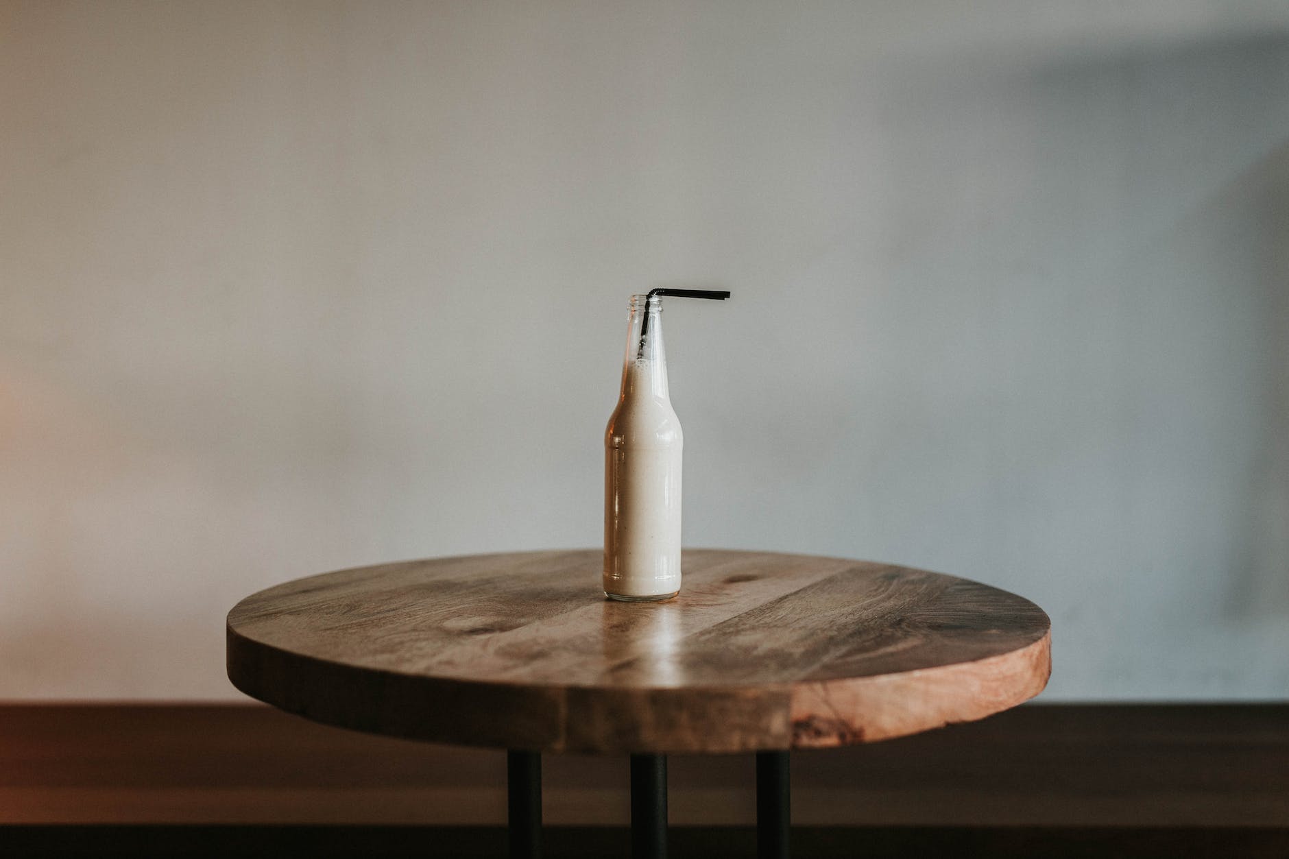 glass bottle filled with black straw on brown wooden table